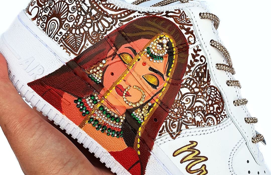 Indian bride in maroon lehenga and jewellery portrait hand painted on white Air Force 1 sneakers with a henna design in the background