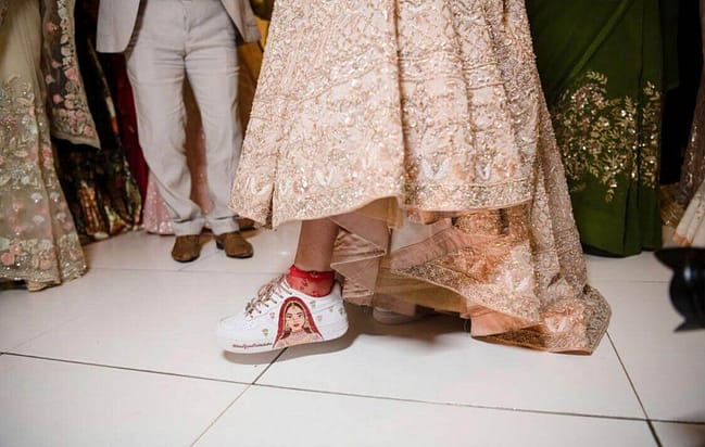 Indian bride in lehenga wearing hand painted bridal Nike AF1 sneakers with bride portrait on them