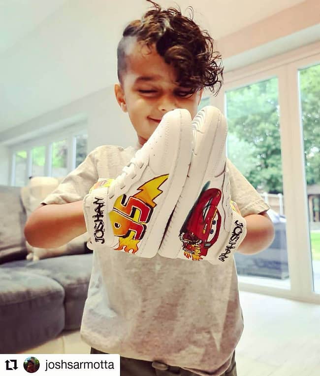 Cute boy holding a pair of kids personalised Cars Lightening McQueen Nike sneakers in his hands