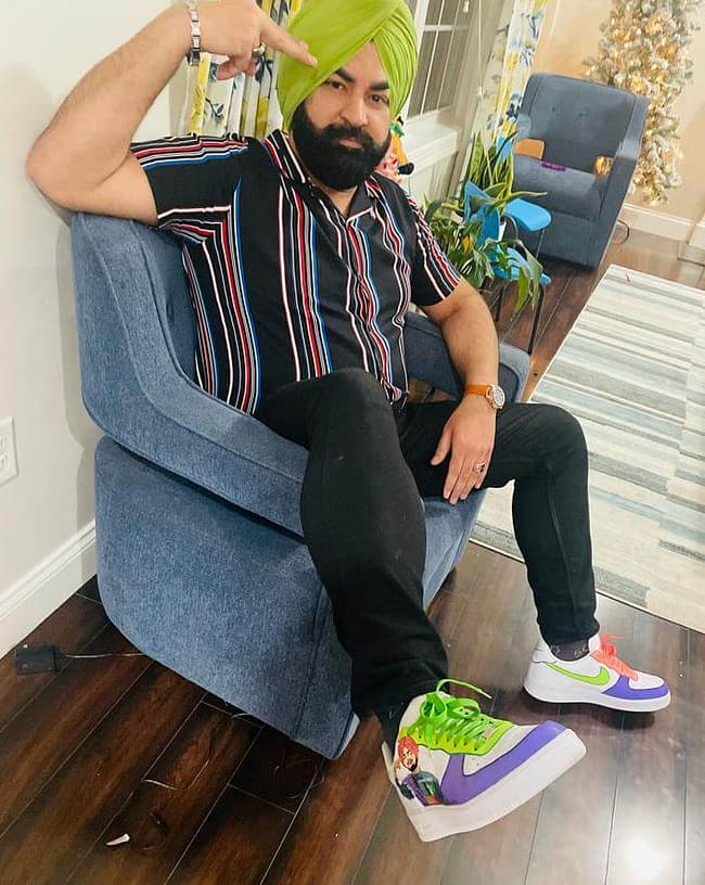 Man sitting wearing colourful neon Sidhu Moosewala hand painted Nike AF1 sneakers